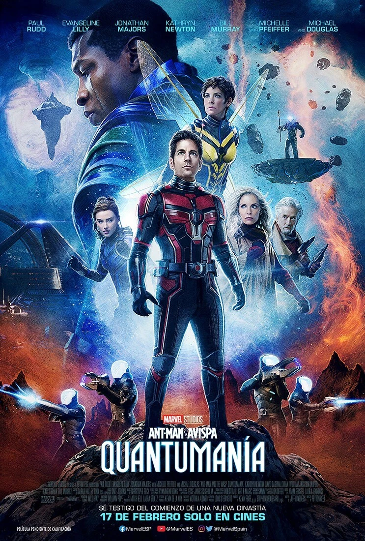 Cartel español de Ant-Man y la Avispa: Quantumanía: Ant-Man con el traje y la cara descubierta en el centro, la Avispa en vuelo detrás, Cassie, Janet van Dyne y Hank Pym a los lados y el rostro de Kang arriba, en un paisaje de naves y criaturas