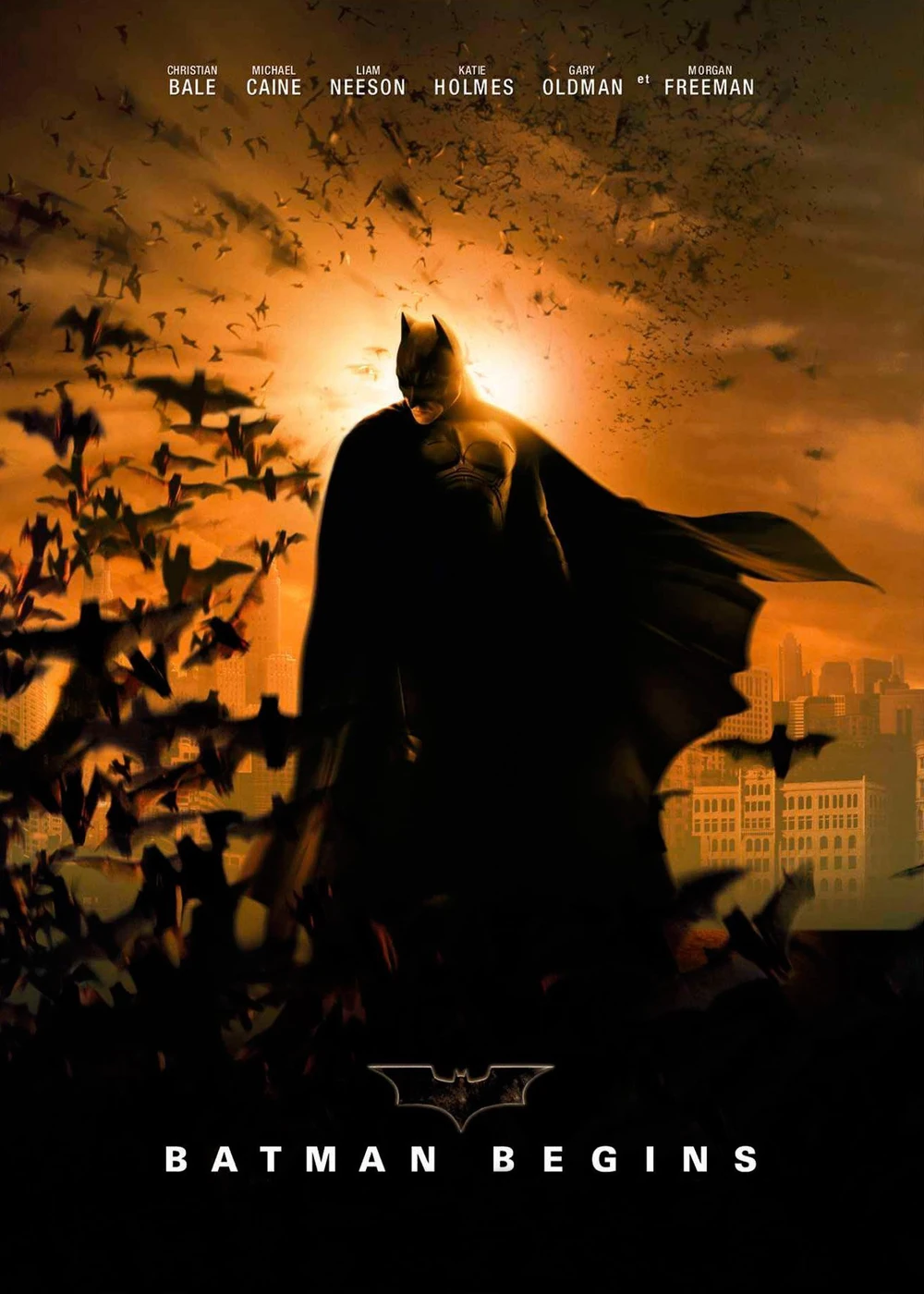 Cartel de Batman Begins: Batman, con la capa desplegada, entre una nube de murciélagos ante un cielo anaranjado; arriba, los nombres del reparto