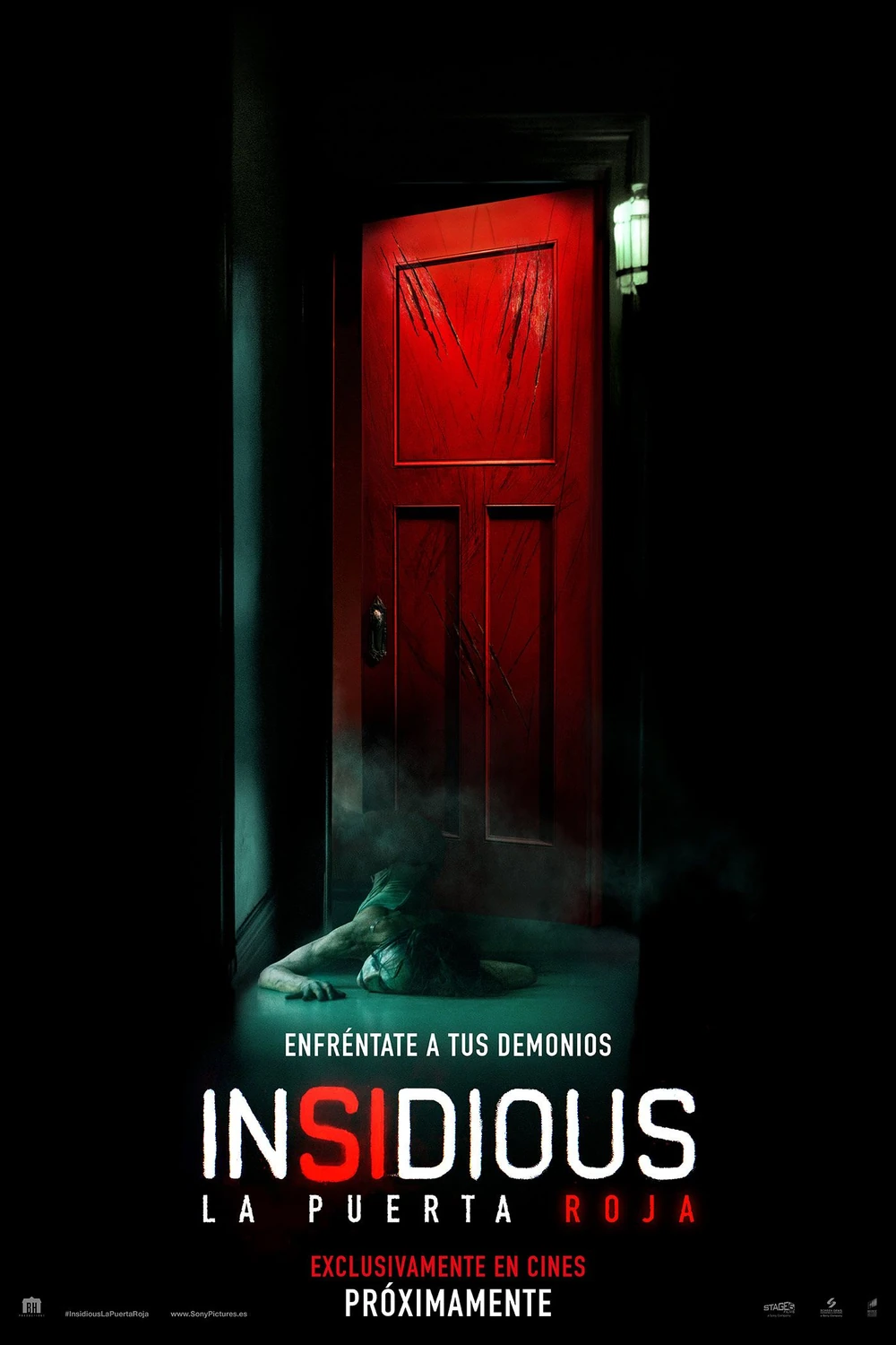 Cartel español de Insidious: La puerta roja: una puerta roja arañada al fondo de un pasillo oscuro, con una figura tendida en el suelo delante, y el lema «Enfréntate a tus demonios»