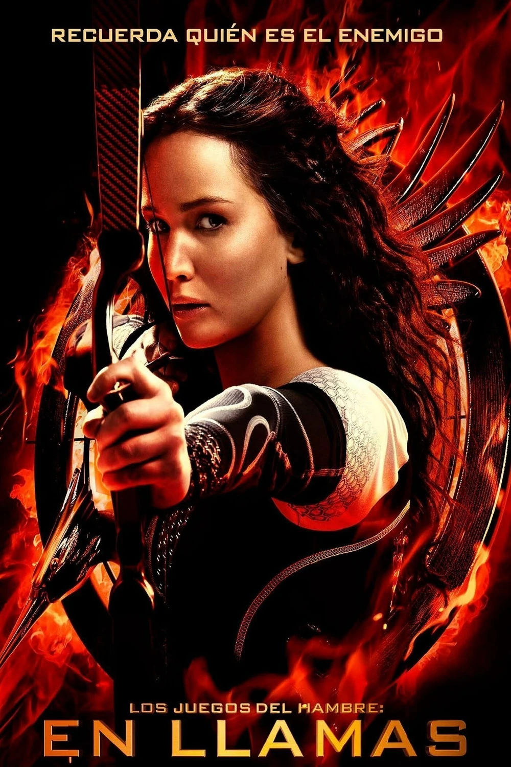 Cartel español de Los juegos del hambre: En llamas: Katniss Everdeen apunta con un arco ante un círculo de fuego, bajo la frase «Recuerda quién es el enemigo»