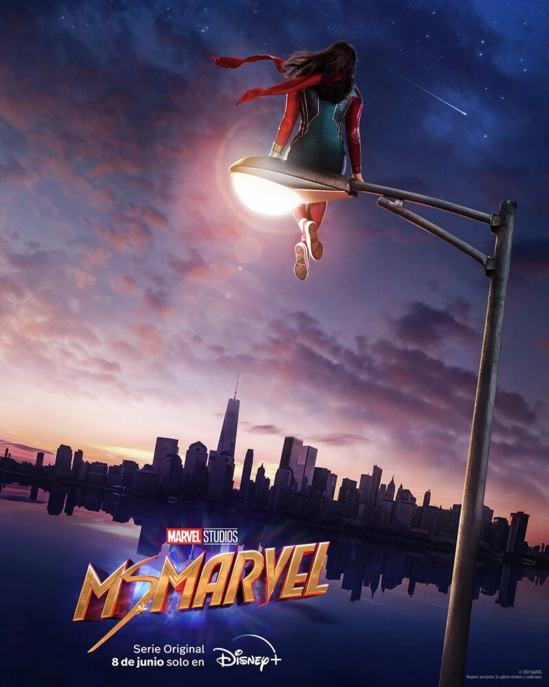 Cartel español de Ms. Marvel: Kamala Khan, de espaldas y con traje de superheroína, sentada sobre una farola encendida frente al perfil de Nueva York al anochecer; abajo, el título y «Serie Original 8 de junio solo en Disney+»